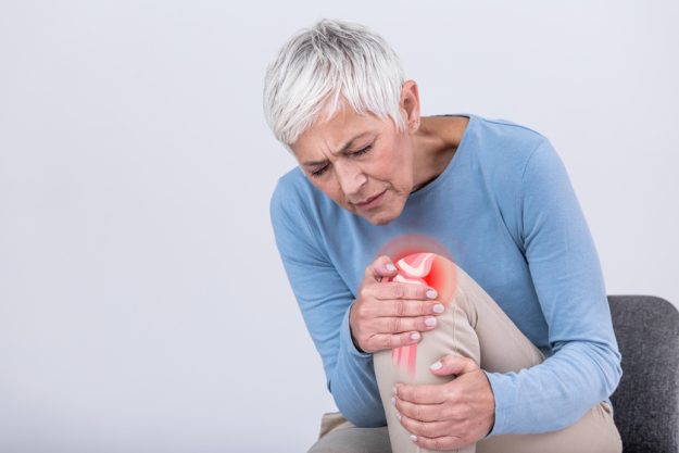 Senior woman holding the knee with pain. Old age, health problem and people concept – senior woman suffering from pain in leg at home. Elderly woman suffering from pain in knee at home Can You Avoid The Risk Of Osteoarthritis As You Age?