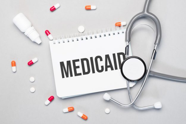 In the notebook is the text medicaid next to a stethoscope, pills and glasses. Does Medicaid Cover The Cost Of Assisted Living In Texas?