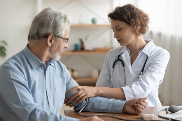 Female doctor measuring senior patient blood pressure at hospital Female doctor measuring senior patient blood pressure at hospital
