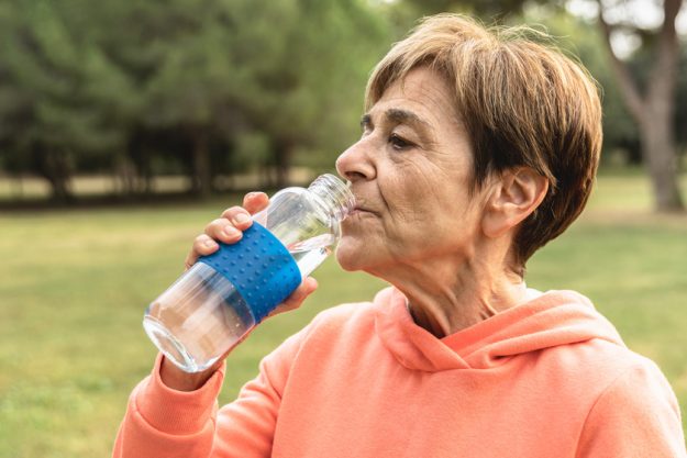 Senior woman drinking water after sport jogging routine outdoor at city park – Elderly exercise and healthy lifestyle Summer Is Coming! 6 Tips To Help Your Aging Parents Stay Hydrated