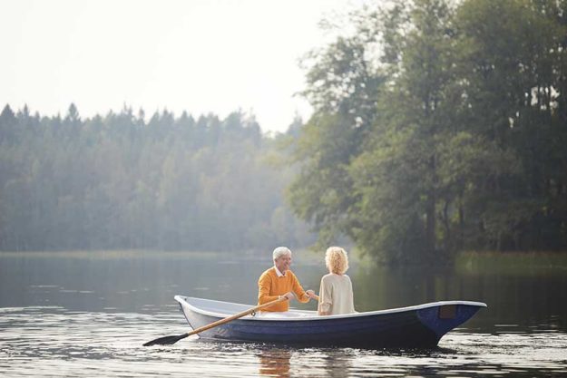 Excited handsome senior boyfriend in yellow sweater sitting on boat Excited handsome senior boyfriend in yellow sweater sitting on boat