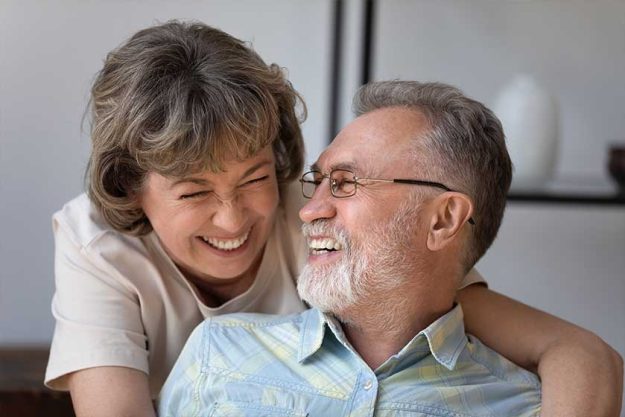 Head shot caring happy older woman cuddling joyful mature husband