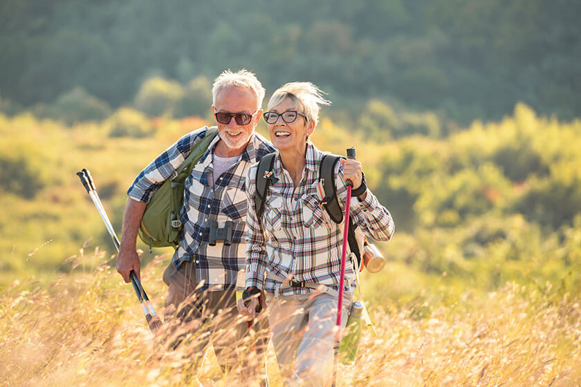 Active senior Caucasian couple hiking in mountains with backpacks and hiking poles