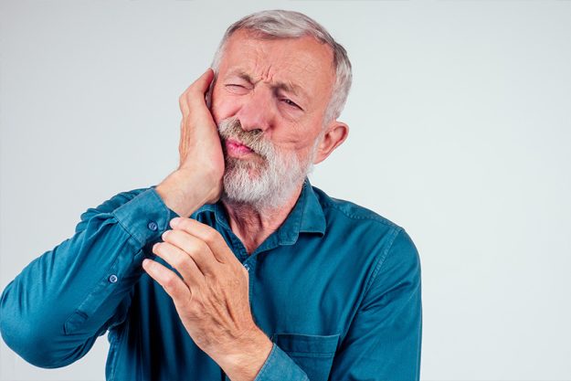 unhappy senior man with closed eyes holding cheek isolated white background