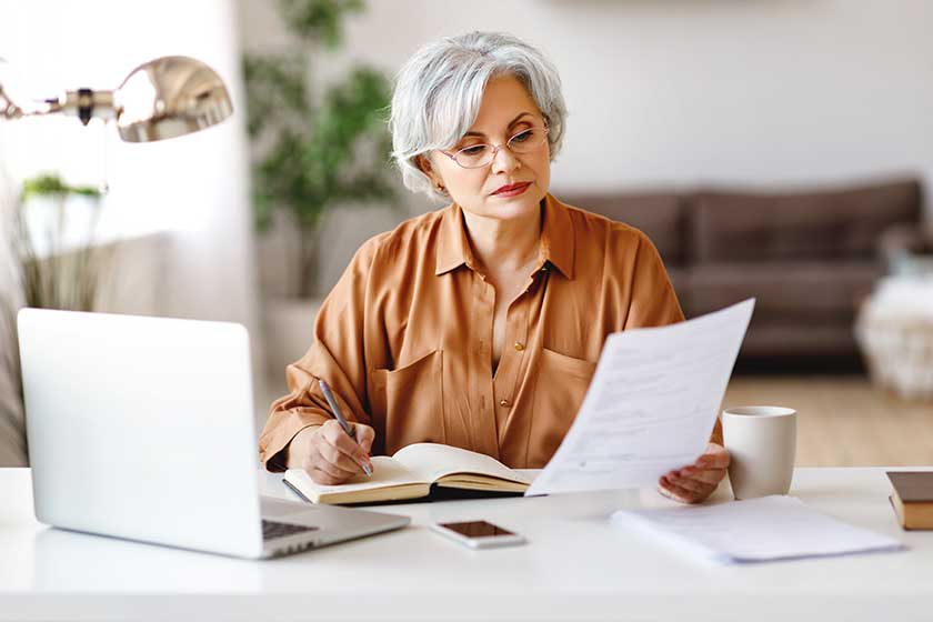 Elderly serious lady in glasses reading document and making notes Elderly serious lady in glasses reading document and making notes