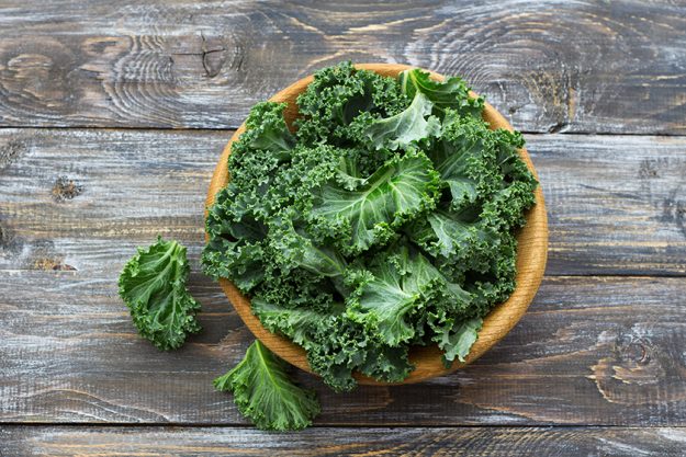 Fresh green curly kale leaves on a wooden table Fresh green curly kale leaves on a wooden table