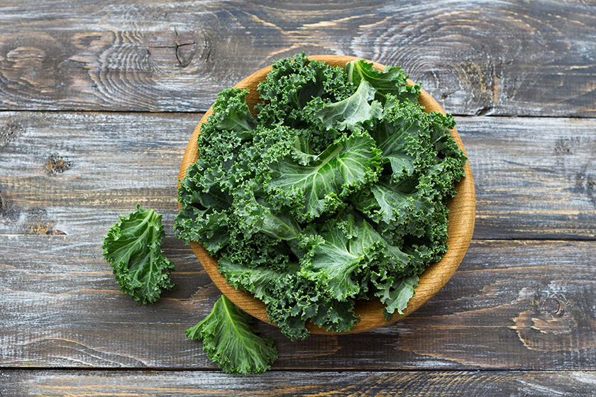 Fresh green curly kale leaves on a wooden table