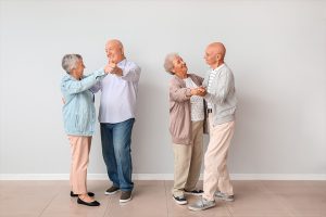 Senior couples dancing near light wall