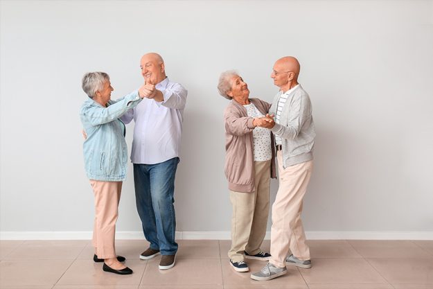 Senior couples dancing near light wall