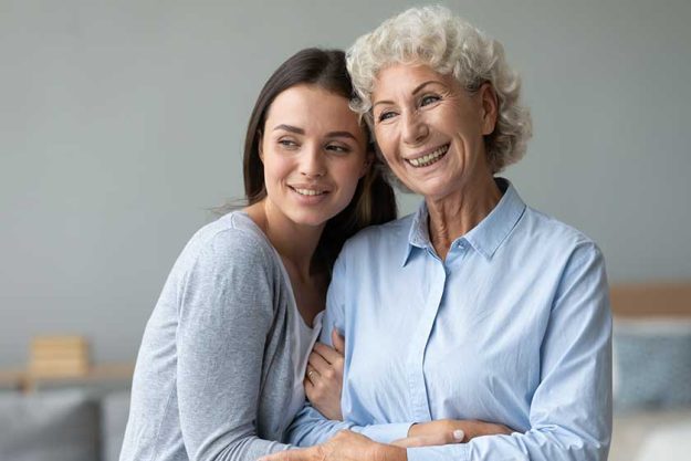 Young granddaughter and happy old grandmother bonding looking away dreaming