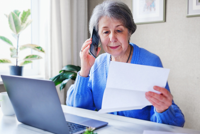 An elderly woman pays taxes or other bills online - A pensioner