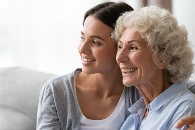 Horizontal image adult granddaughter hugs elderly grandmother