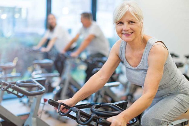 Confident seniors on exercise bikes in spinning class at gym
