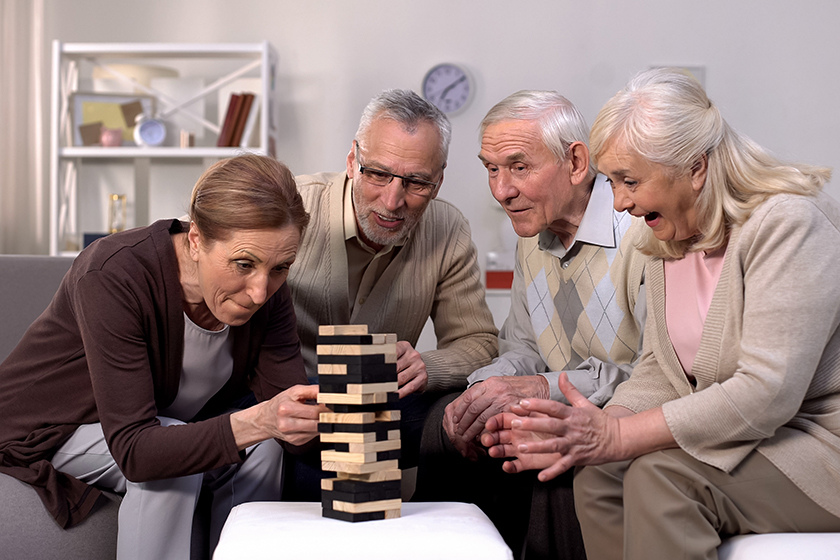 Elderly friends building tower from wooden cubes leisure time in nursing home Elderly friends building tower from wooden cubes leisure time in nursing home