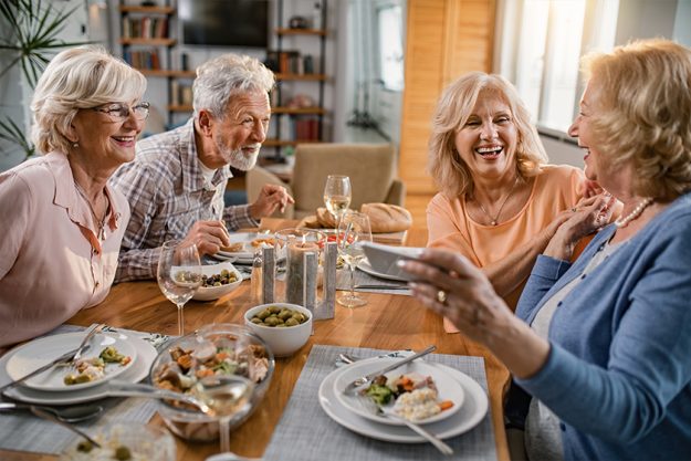 Group of cheerful senior friends having fun at dining table Group of cheerful senior friends having fun at dining table