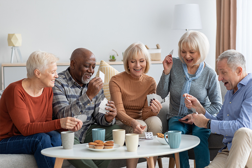 Happy senior friends playing cards while chilling together