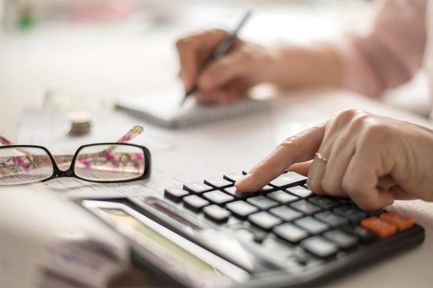 old hands counting finances on a home calculator old hands counting finances on a home calculator