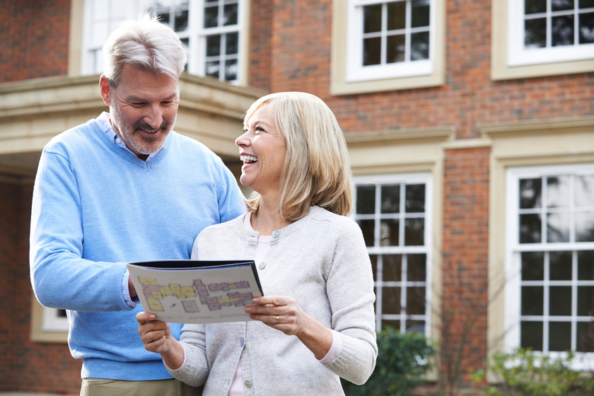 Mature Couple Standing Outside House Looking At Property Details Selling A House To Pay For Assisted Living In Euless, TX: 4 Tips For Seniors