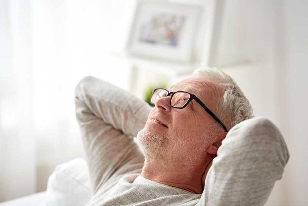 smiling senior man in glasses relaxing on sofa