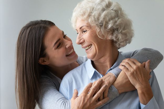 Smiling young woman granddaughter embracing happy old granny or mom Smiling young woman granddaughter embracing happy old granny or mom
