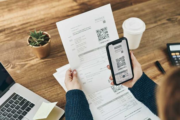 Woman paying invoice scanning QR code from documen