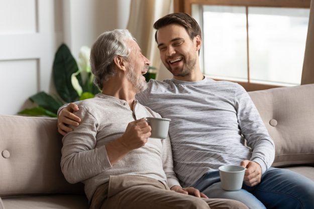 Happy senior dad and adult son relax at home together Happy senior dad and adult son relax at home together