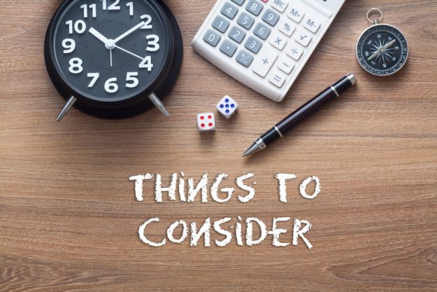 Things to consider written on wooden table with clock,dice,calcu