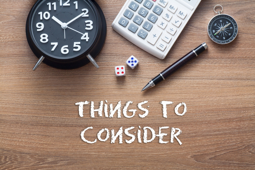 Things to consider written on wooden table with clock,dice,calcu