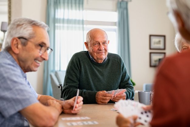 Senior joyful friends playing cards together Assisted Living In Boyce, TX: Myths Vs. Facts