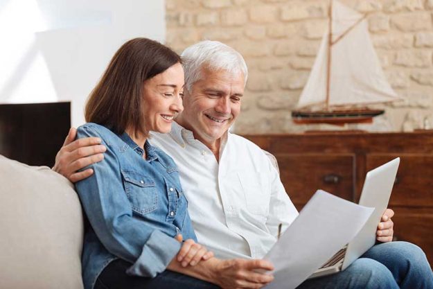 couple using their laptop to pay their bills at home in the living room couple using their laptop to pay their bills at home in the living room
