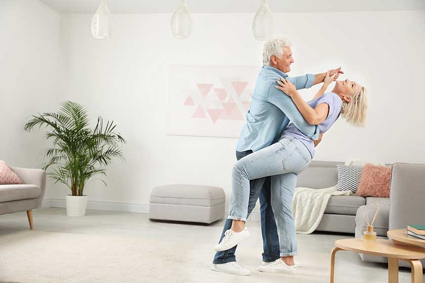 Happy mature couple dancing together in living room Happy mature couple dancing together in living room
