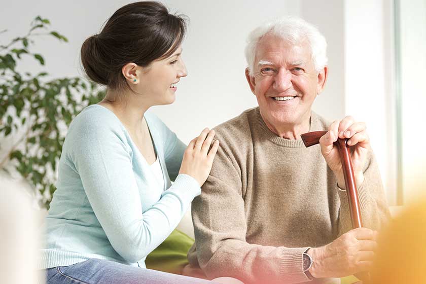 Happy woman supporting smiling senior man with walking stick Happy woman supporting smiling senior man with walking stick