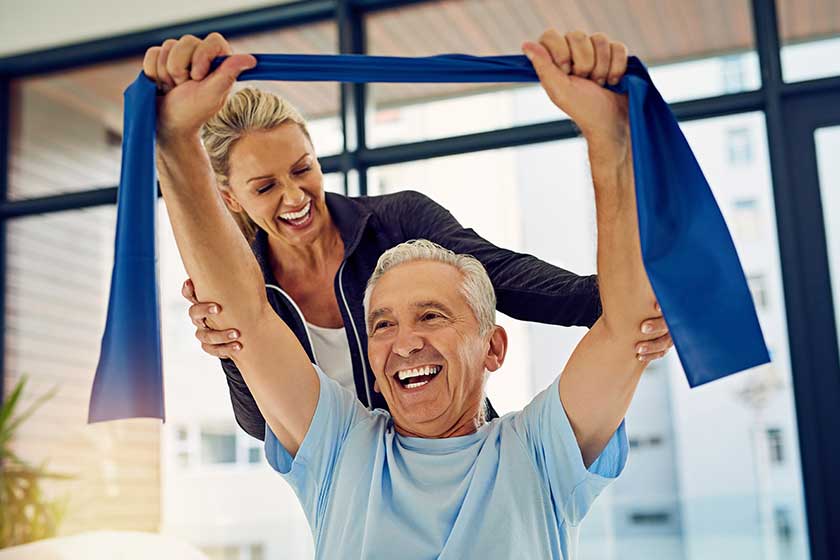 Shot of a physiotherapist helping a senior patient stretch with a stretch band in her office. Shot of a physiotherapist helping a senior patient stretch with a stretch band in her office.