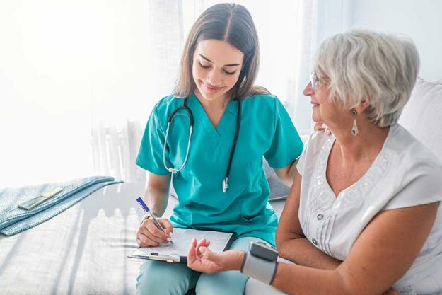 Nurse measuring blood pressure of senior woman at home