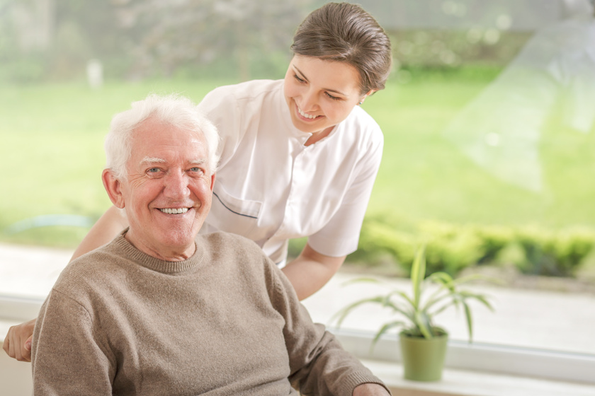 Happy caregiver helping smiling elderly man in the nursing house Happy caregiver helping smiling elderly man in the nursing house