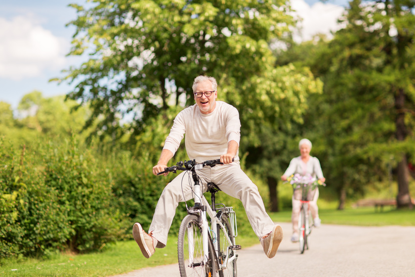 happy senior couple riding bicycles at summer park