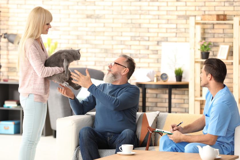 Daughter giving cute cat to her senior father at home Considering A Pet While Aging At Your Retirement Community? Here's What You Need To Know