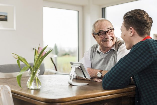 Happy senior man and his grandson sitting at table in the living room Happy senior man and his grandson sitting at table in the living room