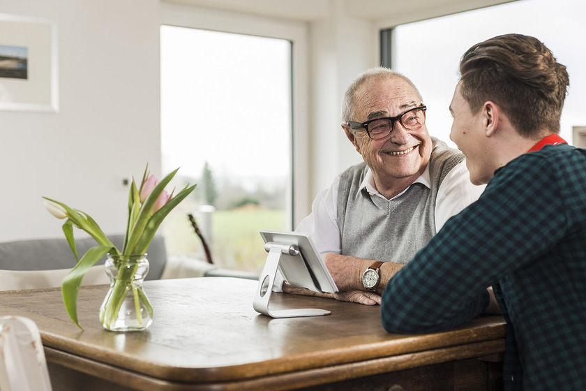 Happy senior man and his grandson sitting at table in the living room