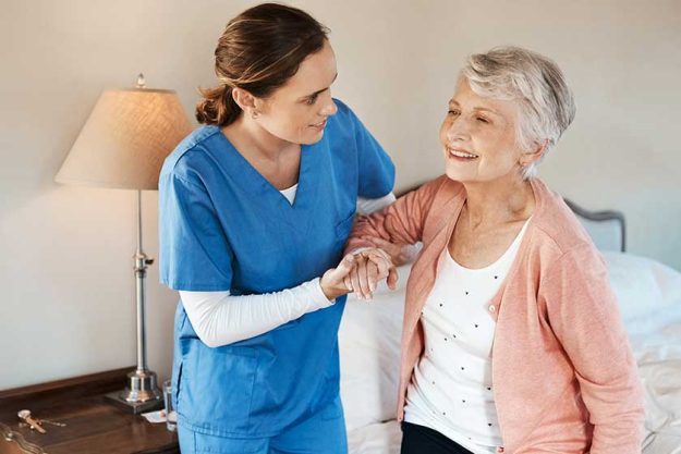 hot of a young nurse helping a senior woman get up from her bed in a nursing home. hot of a young nurse helping a senior woman get up from her bed in a nursing home.