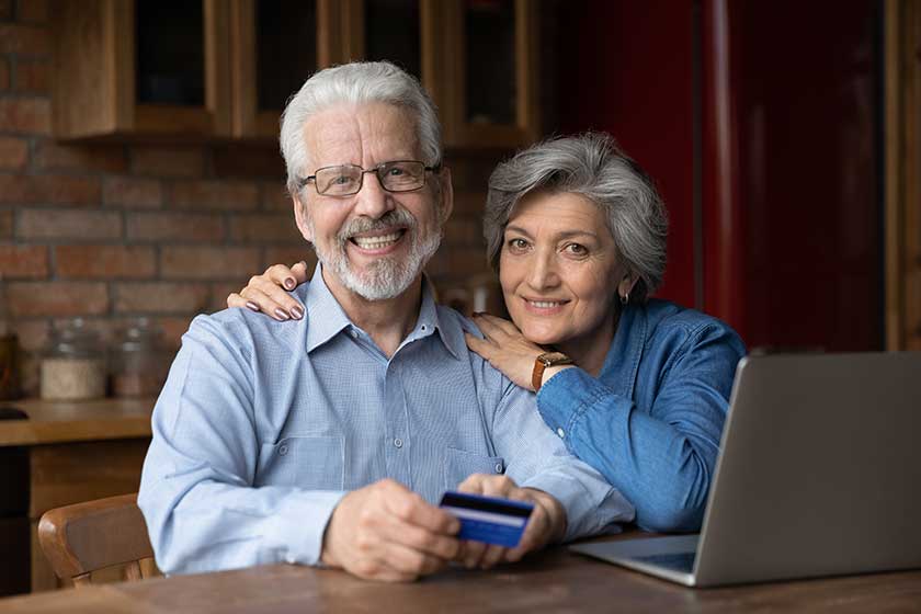 Portrait of happy aged family husband wife on retirement embrace by kitchen table look at camera Portrait of happy aged family husband wife on retirement embrace by kitchen table look at camera