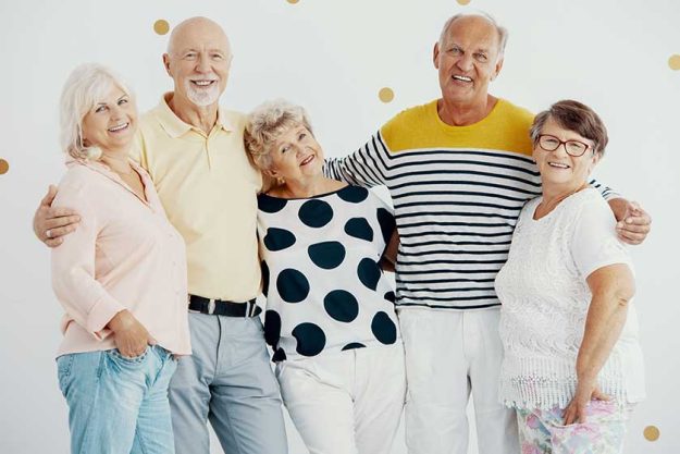 Smiling group of elderly people hugging each other during photo session Smiling group of elderly people hugging each other during photo session