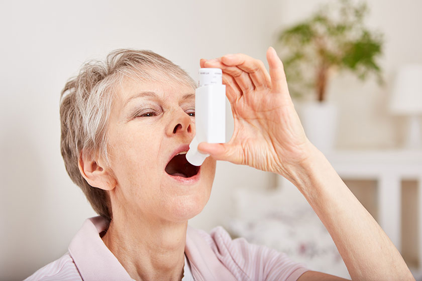 Seniorin benutzt einen Inhalator