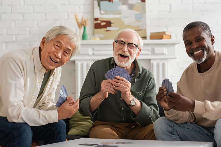 Cheerful interracial friends holding playing cards