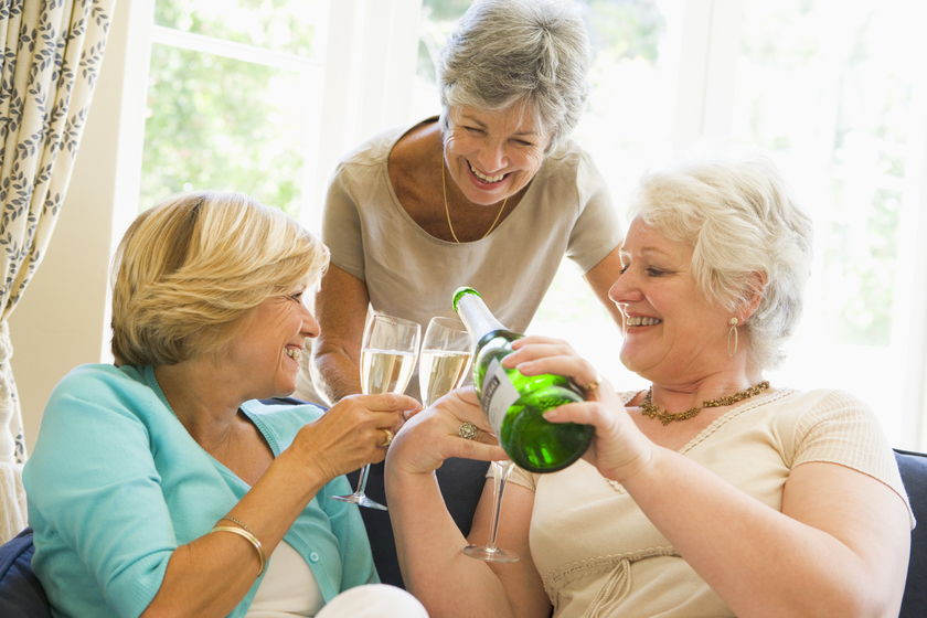 Three women in living room drinking champagne and smiling