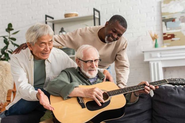 Positive interracial pensioners looking at friend playing