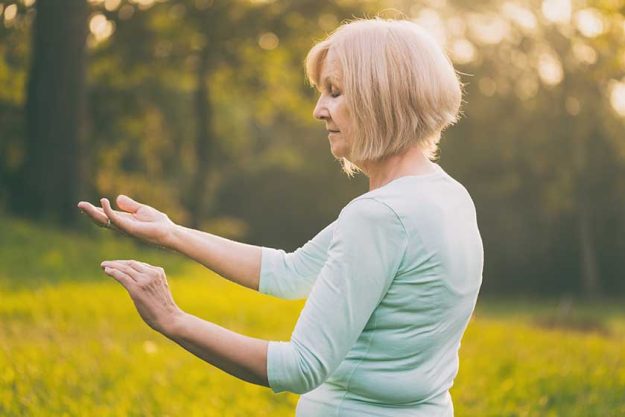 Senior woman enjoys exercise Tai Chi in the nature