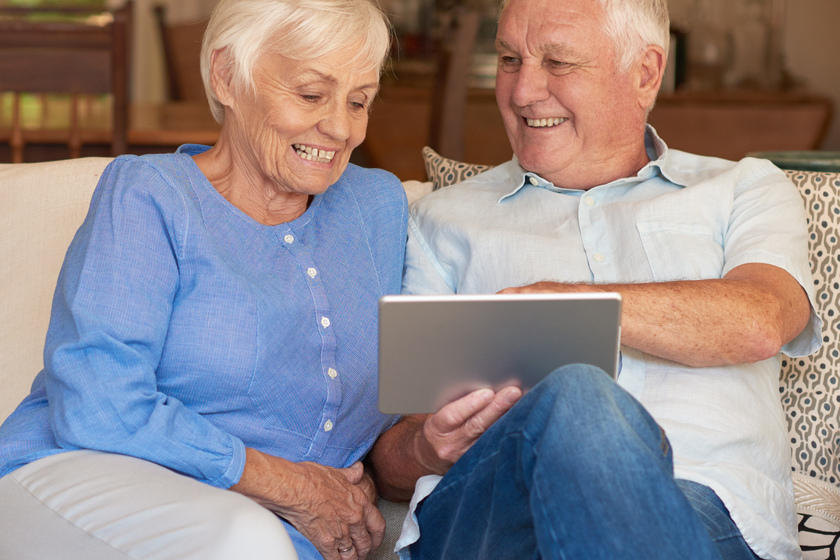 Content seniors using a touchscreen tablet on their couch Why Interior Design Matters When Choosing A Retirement Community In Sterrett, TX