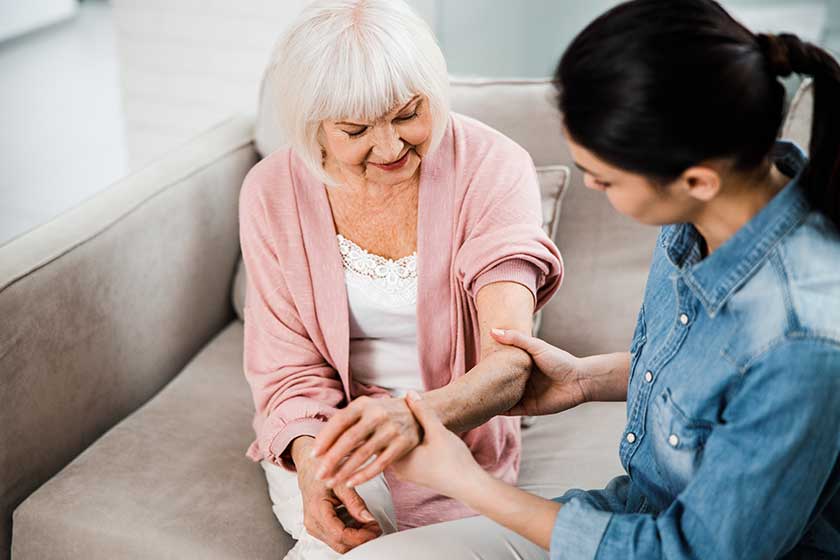 Family doctor holding arm of elderly woman