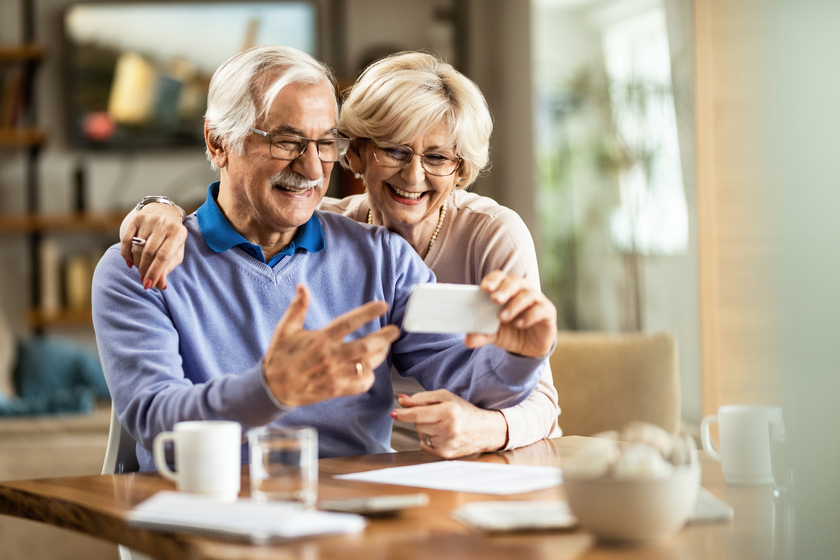 Happy mature couple having a video chat over smart phone at home. Our Senior Home Floor Plans Are Designed To Fit Your Active Retirement
